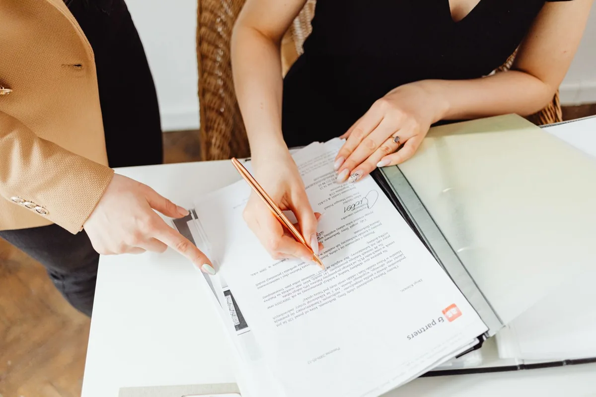 Two people reviewing and signing off on a document at a desk